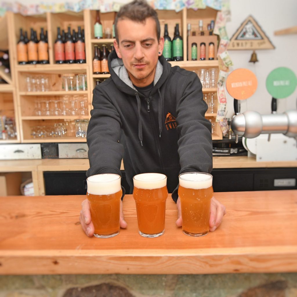Adrien, owner of La Gwpae, serving glasses of draft beer
